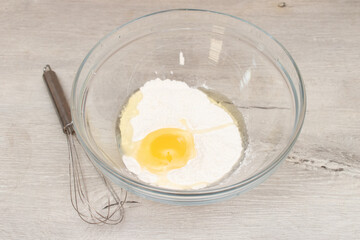 Flour in a bowl, egg and whisk. Preparation of the dough