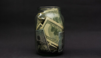 A glass jar full of dollars between one dollar bills. An easy way to save real money © Angelov