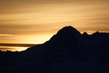 Silhouette of a moutain in switzerland - early morning with strong yellow background