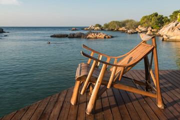 Fototapeta na wymiar Wooden sunbed or deck chair at resort patio by the sea