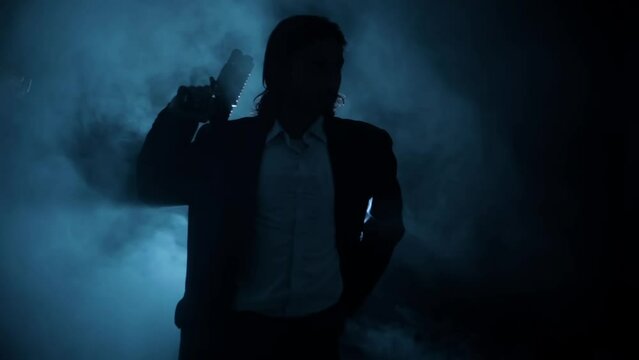 Shot of a young hitman in a blue colored coat with his gun resting on his shoulder HD footage.