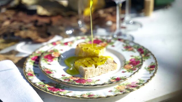 Traditional crusty Italian bruschetta poured with extra virgin olive oil, seasoned with salt and pepper. Tasty grilled bread on plate served in Italian rustic restaurant, fresh olive oil being poured