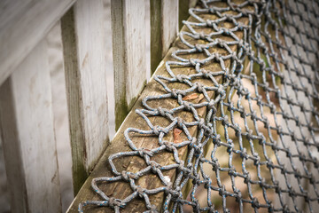 Fabric weaved rope net hanging on wooden plank near wet concrete wall weird urban findings