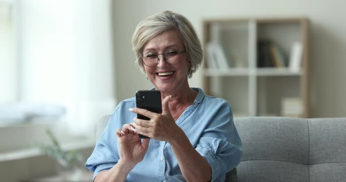 Happy senior woman read sms with good news, bank notice, message from friend looks overjoyed, enjoy great sell-out notification, auction or lottery victory, relish moment of success and achievement
