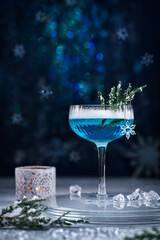 Alcoholic cocktail with gin decorated with a snowflake on a blue background. Cocktail Blue Lagoon. A blue alcohol drink.