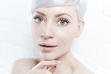 Closeup portrait of beautiful young woman with green eyes and white hair.