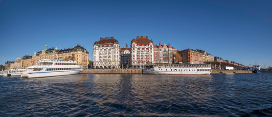 Panorama, pier at the jetty Strandvägen with commuter boats, waterfront hotels, offices and apartment buildings a sunny winter day in Stockholm