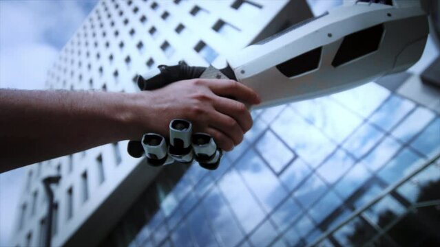 View from below of handshake of human and artificial intelligence. Robot shaking hand of man on background of modern glass building. City. Business concept. Congratulations