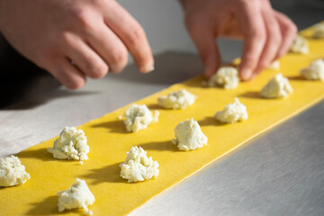 Young Man Chef making ravioli pasta. Italian food home made pasta ravioli on metal background.