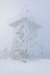 Misty winter scenery with observation tower on top of a mountain