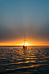 sailboat sailing at sea towards the sunset