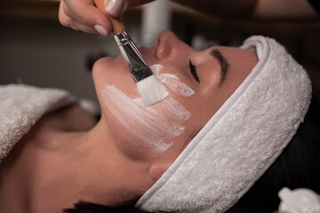 a beautiful client woman on a cosmetology procedure with a beautician, does facial care for youthful skin