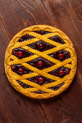 Cherry shortcrust pastry pie decorated with cherries and pastry grill.