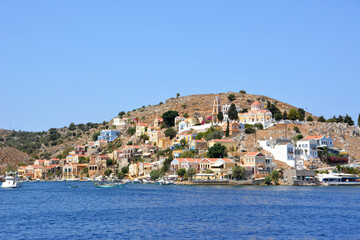 Fototapeta na wymiar greek island Symi with multicolored buildings, monastery and waterfront with blue sea