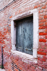 Fototapeta na wymiar Close up old red brick wall building with shutters window concept photo. Street scene,