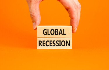Global recession symbol. Concept words Global recession on wooden blocks. Beautiful orange table orange background. Businessman hand. Business and global recession concept. Copy space.