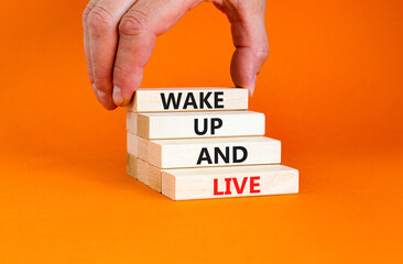 Wake up and live symbol. Concept words Wake up and live on wooden blocks. Beautiful orange table orange background. Businessman hand. Business lifestyle wake up and live concept. Copy space.