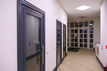 A corridor in an urban-type office building. Modern interior of the lobby of an office building with glass doors and clean white walls. A lighted long corridor in a modern business center.