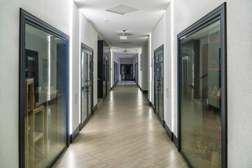 A corridor in an urban-type office building. Modern interior of the lobby of an office building with glass doors and clean white walls. A lighted long corridor in a modern business center.
