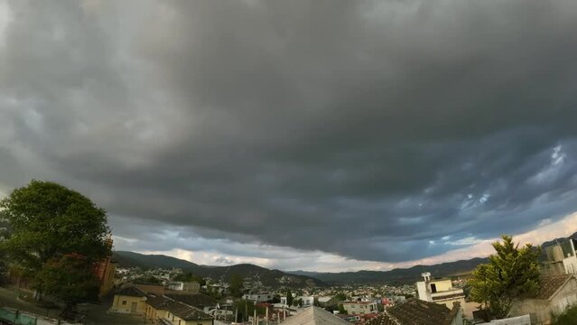 Nubes negras form&aacute;ndose para fuerte lluvia sobre pueblo mexicano, se capta la formaci&oacute;n de un tornado que pasa sobre &eacute;l. 
