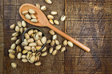 Portion of pistachio in clay bowl and wooden spoon. Space for text