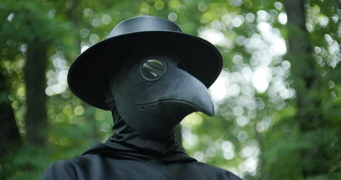 Plague doctor standing in woods in slow motion