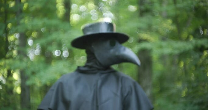 Plague doctor standing in forest in slow motion