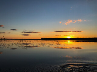 Sunset on a lake with blue skies and clouds reflecting in the water. Tourism and travel concept.