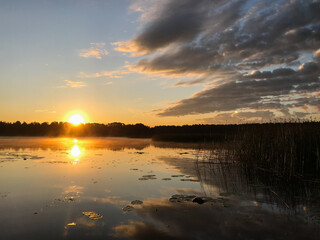 Sunset on a lake with blue skies and clouds reflecting in the water. Tourism and travel concept.