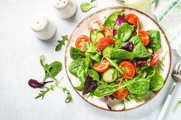 Salad from green leaves and vegetables. Fresh green salad in white plate. Top view.