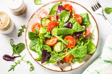 Salad from green leaves and vegetables. Fresh green salad in white plate. Top view.