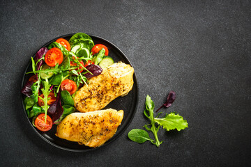 Healthy food plate, keto diet. Green salad with chicken fillet on black table. Top view with copy space.