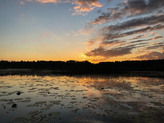 Sunset on a lake with blue skies and clouds reflecting in the water. Tourism and travel concept.