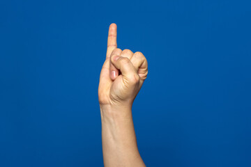 Man's hand with the little finger raised as a sign of promise or oath, isolated on blue background.