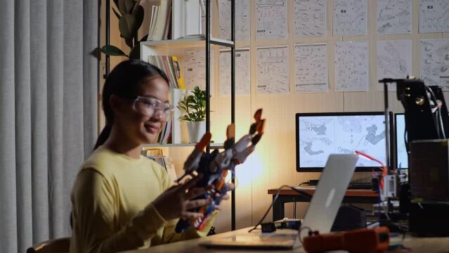 Teen Asian Girl Walking To Look At The Pictures On The Wall While Working About A Cyborg Hand At Home
