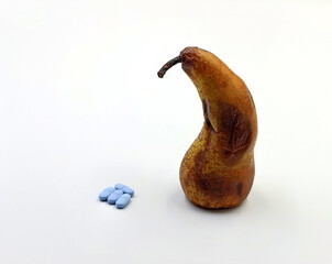 A very ripe pear next to medicines or blue pills. Concept of erection problems, impotence or...