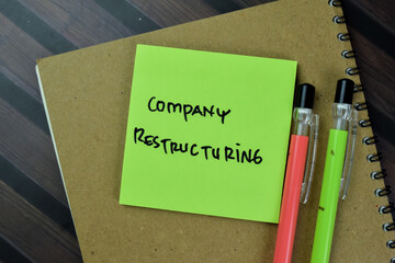 Concept of Company Restructuring write on sticky notes isolated on Wooden Table.