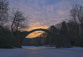 Zelfklevend Fotobehang Rakotzbrücke Rakotzbrücke Kromlau im Winter mit schönen Sonnenaufgang
