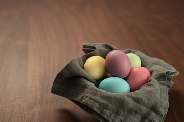 Easter eggs in a bowl with napkin on walnut wood table with copy space