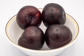 Plums in a bowl on a white background