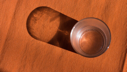 Obraz premium Glass of water with shadow aesthetic on orange background