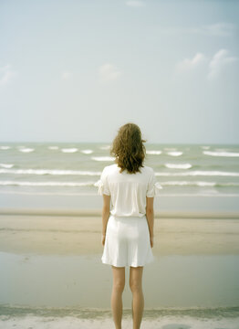 a girl in a white dress stands on the beach, against the backdrop of the sea, standing with his back to the camera, ai art 