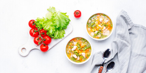 Light vegetable soup with chicken, corn and green beans. Comfort food. White table background, top view banner