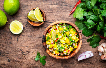 Spicy mango salsa sauce with red chili peppers, onion, garlic lime and cilantro, rustic wooden table background, top view