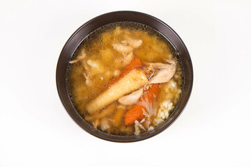 Chicken soup with noodle and carrot and parsley roots, chicken meat visible, in a bowl on a white background