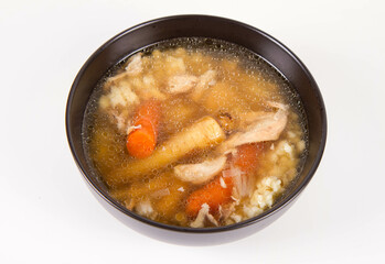 Chicken soup with noodle and carrot and parsley roots, chicken meat visible, in a bowl on a white background