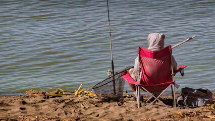 Person sitting in a chair while fishing on the beach