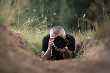 Masked wildlife photographer waiting for game in a game refuge, hidden and well hidden like a chameleon, with a long telephoto lens, nature photography