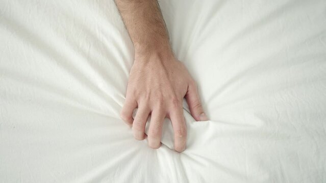 Young hispanic man having orgasm on bed at bedroom