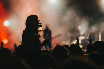 Silhouette of a woman with raised hands on a concert